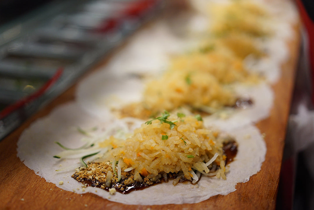 Traditional popiah opened to show turnip, egg and crispy bits on handmade popiah skin